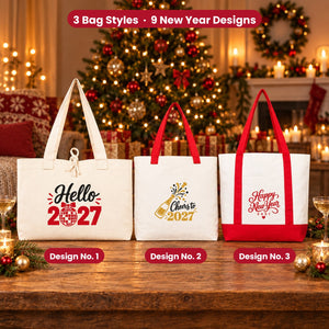 Three natural canvas New Year 2027 tote bags with Design No. 1 Hello 2027, No. 2 Cheers to 2027 and No. 3 Happy New Year 2027 on a wooden table by a lit holiday tree