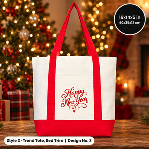 Canvas tote bag with red handles and red base printed Happy New Year 2027 in red script on a wooden table by a holiday tree and fireplace