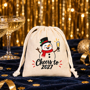 Cotton pouch with a natural cord printed with a Cheers to 2027 snowman on a navy velvet New Year's Eve table with champagne coupes, gold confetti and a disco ball