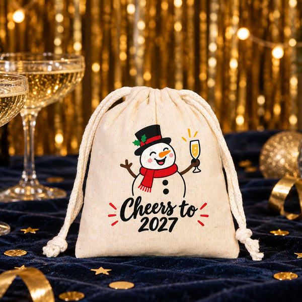 Cotton pouch with a natural cord printed with a Cheers to 2027 snowman on a navy velvet New Year's Eve table with champagne coupes, gold confetti and a disco ball