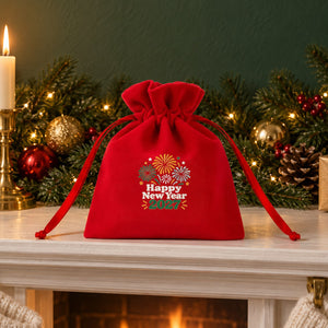 Red velvet drawstring pouch printed with a Happy New Year 2027 fireworks design on a white fireplace mantel with candles, a garland and knitted stockings