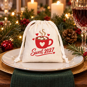 Cotton pouch with a natural cord printed with a Sweet 2027 hot cocoa design on a dinner plate at a festive Christmas place setting as a party favour