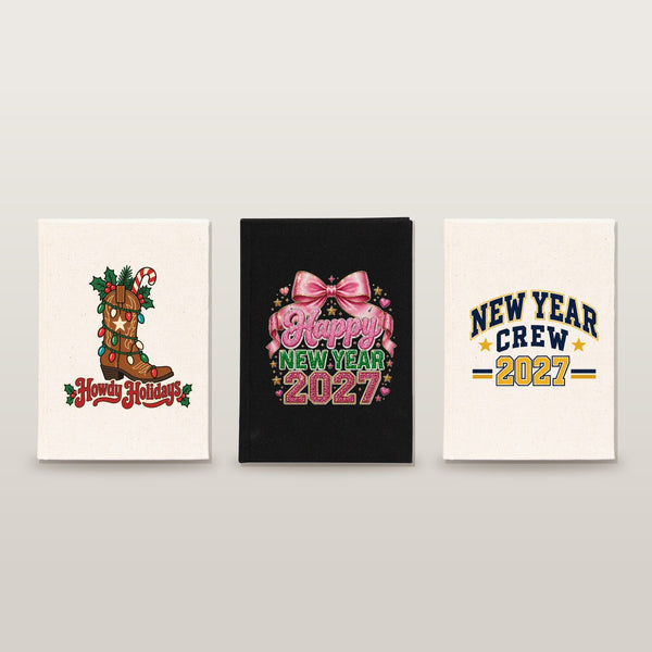 Studio photo of three canvas notebooks with Howdy Holidays cowboy boot, pink bow Happy New Year 2027 and New Year Crew 2027 prints