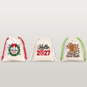 Three cotton drawstring pouches with red, natural and green cords printed with Happy New Year 2027 wreath, Hello 2027 and Baking Spirits Bright designs on a plain studio background