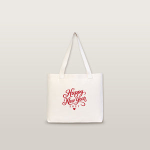 Studio photo of a large canvas tote bag with beige knitted straps and a red Happy New Year 2027 script print