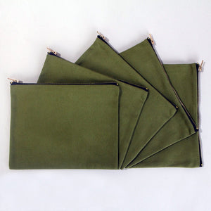 Real photo of five olive green cotton clutch bags fanned out, showing the flat pouch and brass zippers
