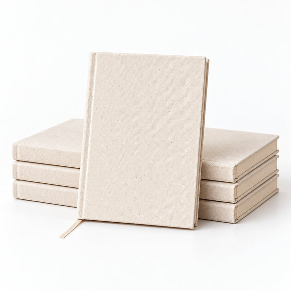 Stacks of blank natural canvas notebooks on a white studio surface – bulk and wholesale orders | Pamusan.com