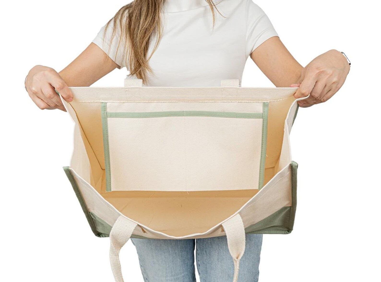 Hands holding wide-open canvas tote bag – shows large capacity and sturdy build