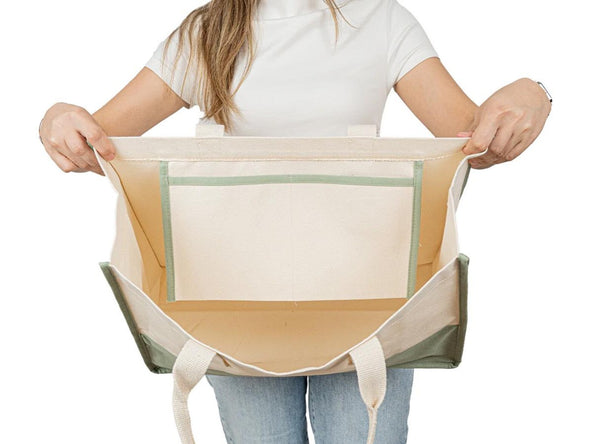 Hands holding wide-open canvas tote bag – shows large capacity and sturdy build