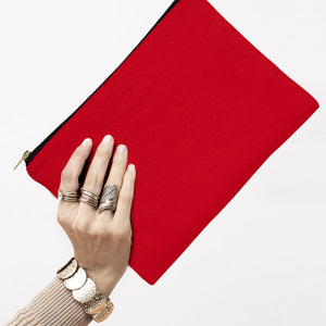 Red clutch held by a hand with multiple rings on a white background