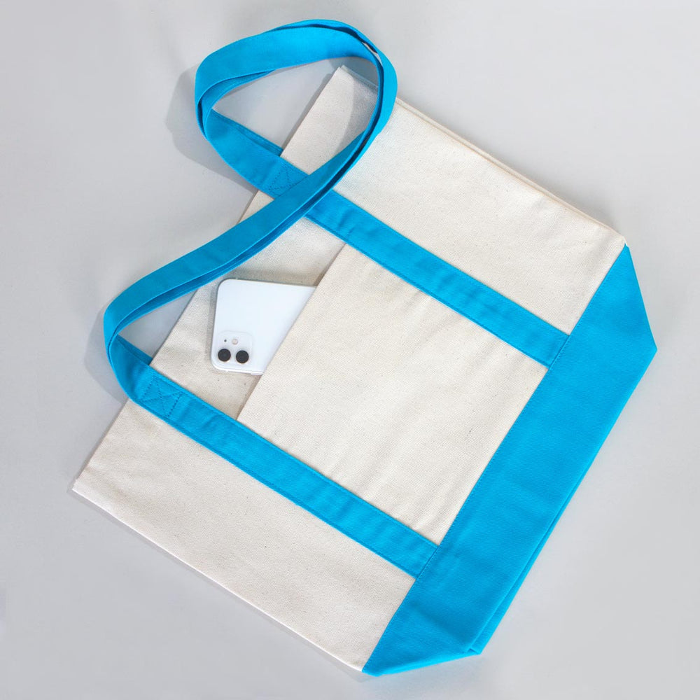 Beige tote bag with blue handles and bottom on a wooden surface